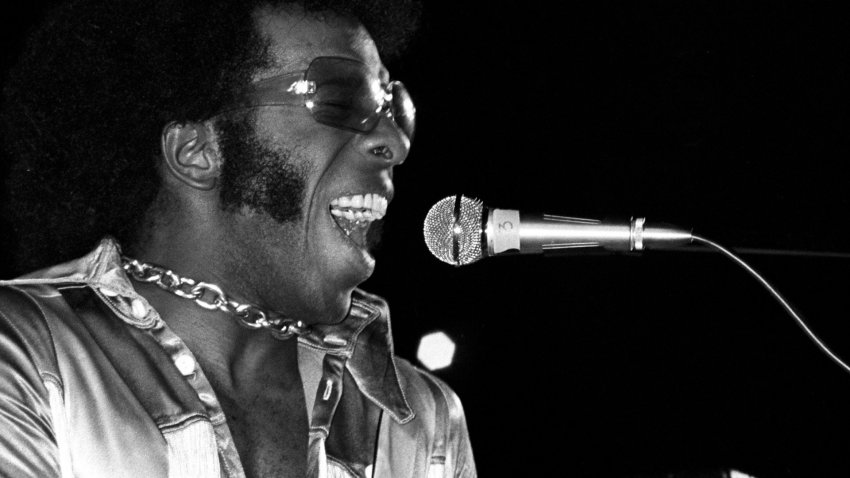Sly Stone sings into a microphone